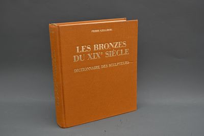 un livre orange posé sur une table près d'un mur gris