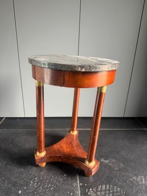 une vieille table en bois avec un plateau en marbre, posée sur un sol carrelé