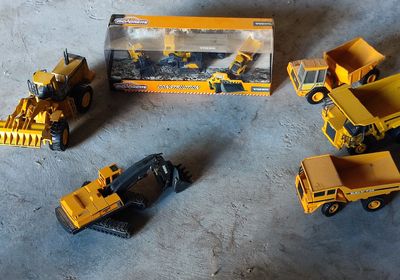 trois engins de chantier miniatures posés par terre