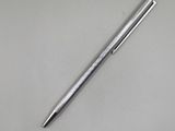 un stylo argenté posé sur une table blanche, à côté d'un stylo noir