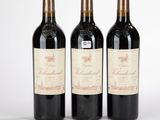 trois bouteilles de vin rouge posées l'une à côté de l'autre sur une surface blanche