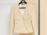 une veste beige suspendue à un cintre devant un mur beige