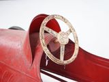 a red toy car with a steering and a steering wheel