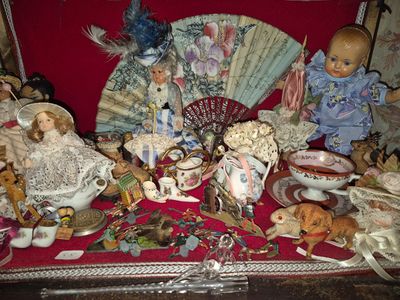 de nombreuses poupées et figurines posées sur une table, avec un ventilateur