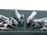 three silver figurines of dogs on a green box