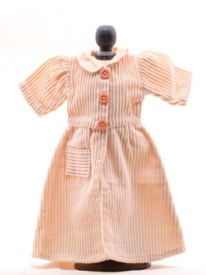 une petite poupée vêtue d'une robe, posée sur un mannequin