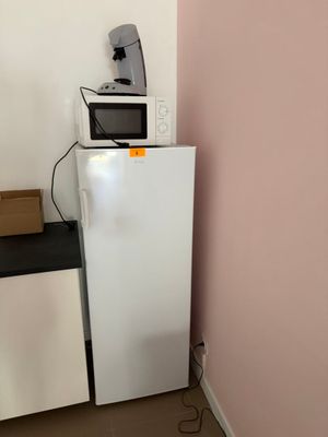 un réfrigérateur blanc et un micro-ondes dans une petite pièce