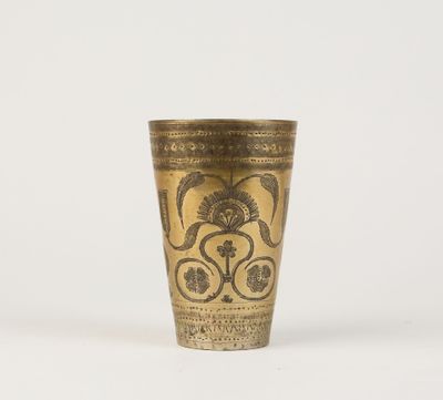 une vieille tasse en laiton ornée d'un motif floral