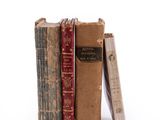 several old books are stacked on top of each other on a white surface