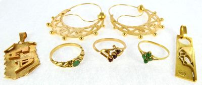several gold rings and pendants on a white surface