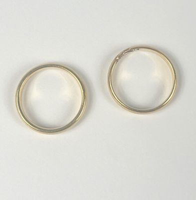two gold rings on a white surface with a white background