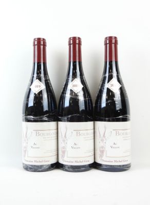 trois bouteilles de vin rouge sont alignées sur une surface blanche
