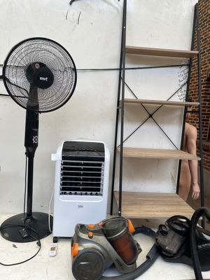 a room with a fan, a table, and other items on the floor