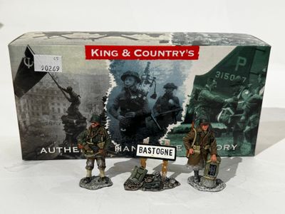 trois figurines représentant des hommes en uniforme militaire sont disposées devant une boîte