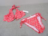 une paire de bikinis rouges posée sur un lit, avec une étiquette dessus
