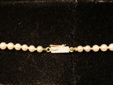 a close up of a necklace with pearls on a mannequin