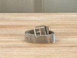 silver metal belt on a wooden surface with a gray background