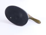 a black pan with a green handle on a white surface