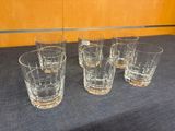 four glasses are lined up on a table in front of a wooden wall