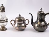 three silver teapots and a salt shaker on a white background