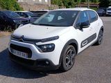 La petite voiture blanche est garée sur le parking, à côté d'autres voitures.