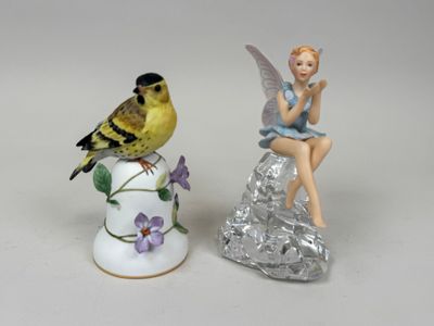 a figurine of a girl sitting on a vase next to a bird