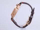 a close up of a watch on a clear stand on a white surface