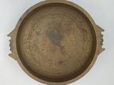 a brown metal bowl with a handle on a white surface
