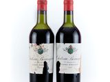 two bottles of red wine sitting next to each other on a white surface