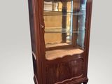 une vitrine ancienne dotée d'une porte vitrée et d'un socle en bois