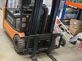 un chariot élévateur dans un entrepôt rempli de palettes et de cartons