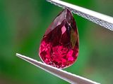 un gros plan d'un diamant rose tenu par une paire de pinces
