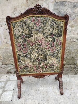 une vieille chaise dont le dossier est recouvert d'un tissu à motifs floraux et dont la structure est en bois