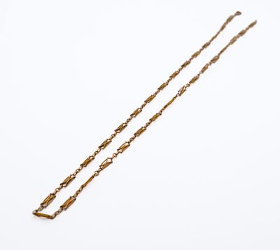 a gold necklace with a long chain on a white background