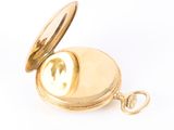 a gold pocket watch sitting on a white surface