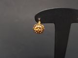 a close up of a pair of gold earrings on a black stand