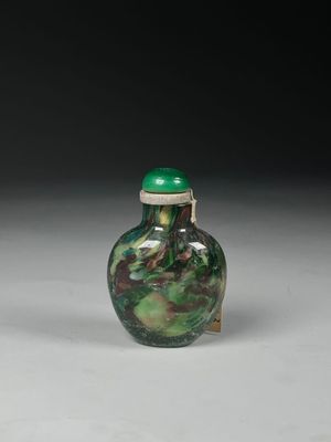 un vase vert et blanc posé sur une surface blanche