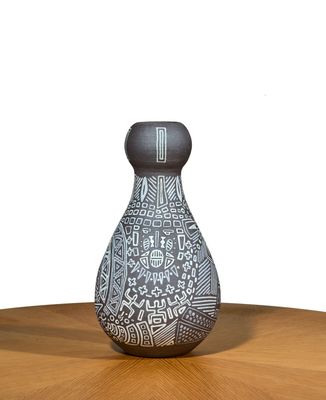 a black and white vase sitting on a wooden table