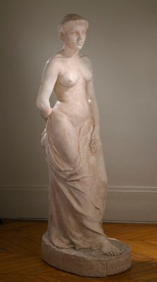 statue d'une femme debout sur un parquet, dans une pièce