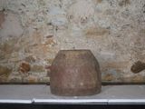 un grand vase en pierre posé sur une table devant un mur de briques