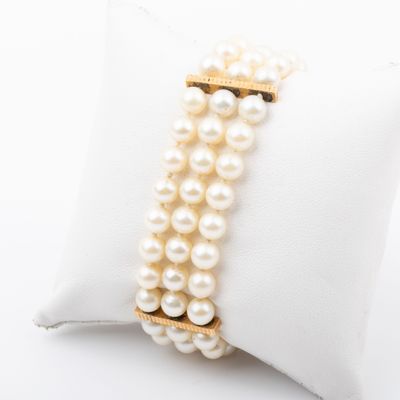 a close up of a bracelet with pearls on a pillow