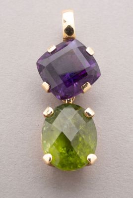 a close up of a green and purple stone pendant on a white surface