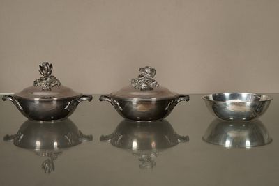 trois plats en argent posés sur une table en verre