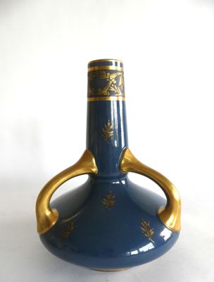 un vase bleu orné de motifs dorés sur un fond blanc