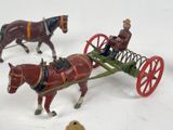 two figurines of horses pulling a wagon with a man on it