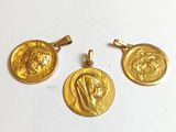 un gros plan sur trois pendentifs en forme de pièces d'or posés sur une surface blanche