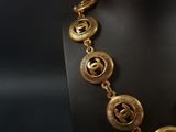 a gold necklace on a mannequin display with a black background