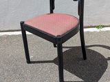 une chaise noire avec une assise rose, posée sur le trottoir