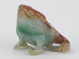 un gros plan d'une figurine représentant une grenouille posée sur une surface blanche