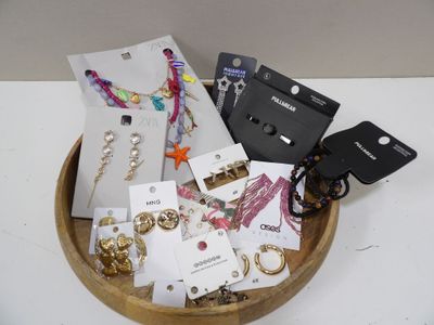 un bol en bois rempli d'un assortiment de bijoux et de boucles d'oreilles